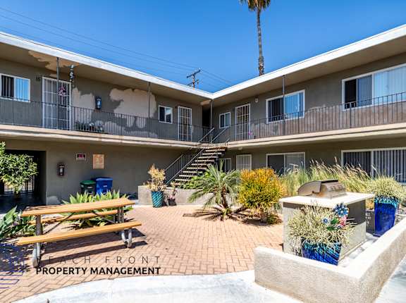 A courtyard with a bench and a planter in front of a building with the words "Peach Front Property Management" on the ground.
