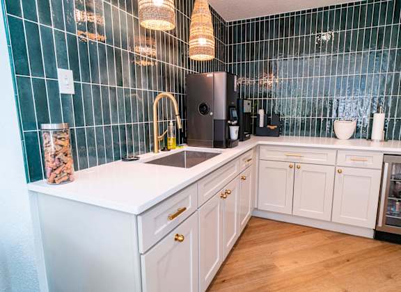A kitchen with a white countertop and a black refrigerator.
