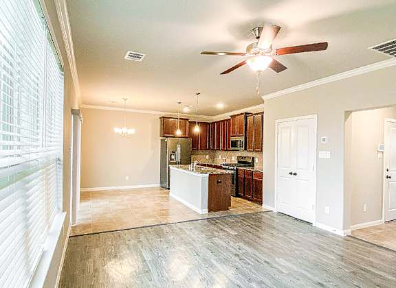 a kitchen and living room with a ceiling fan