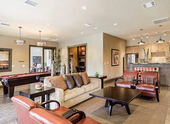 A living room with a pool table and leather chairs.