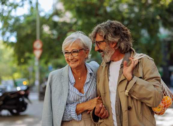 an older man and woman walking down the street together