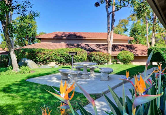 a stone picnic table in a garden in front of a house