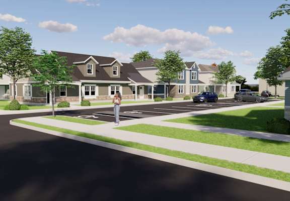 A person stands on a crosswalk in front of a house.