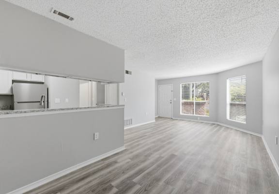 A spacious room with wooden flooring and white walls.