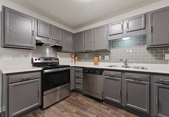 A kitchen with stainless steel appliances and grey cabinetry