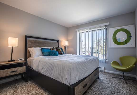 a bedroom with a bed and a chair and a window