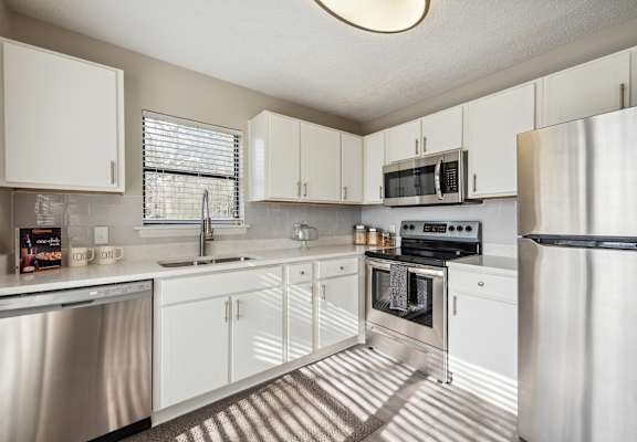 A modern kitchen with white cabinets and stainless steel appliances.