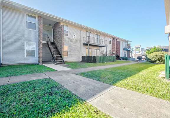Apartment complex with a green fence and a clear sky.