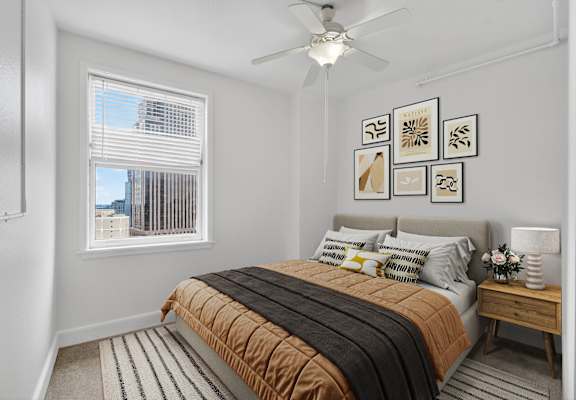 A bedroom with a bed, a ceiling fan, and pictures on the wall.
