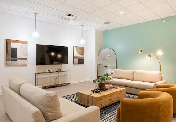 A living room with a sofa, chairs, and a television.