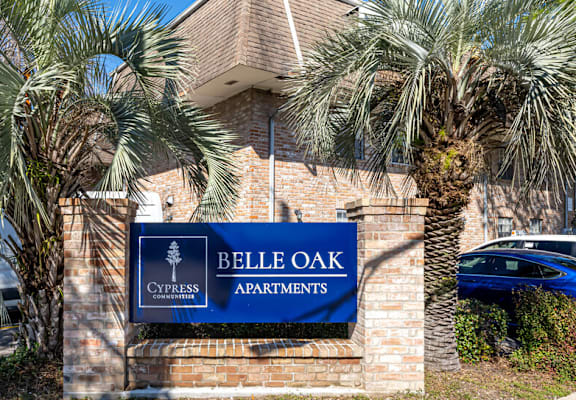 A sign for Belle Oak Apartments is displayed in front of a building.