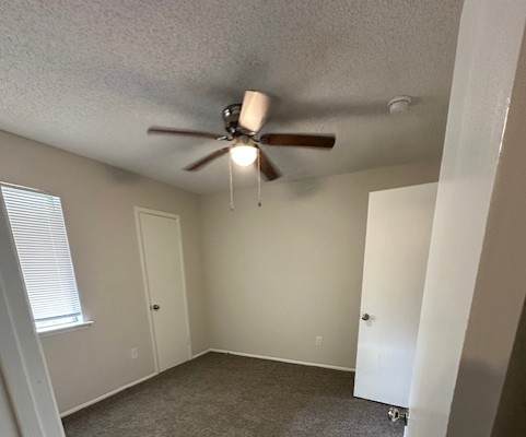 A room with a ceiling fan and carpeted floor.