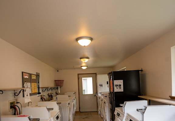 a room full of washers and dryers with a door at the end of the room