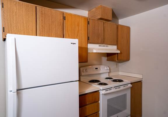 a kitchen with white appliances and wooden cabinets