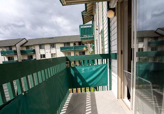a balcony with a green fence and a cloudy sky