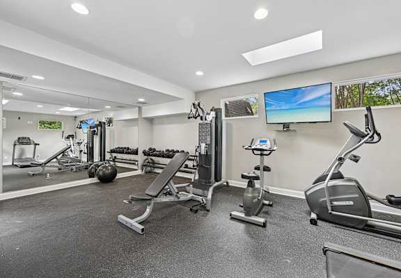 A spacious gym with a variety of equipment including treadmills, stationary bikes, and weight machines.