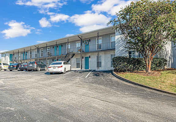 A white car is parked in a parking lot in front of a building.