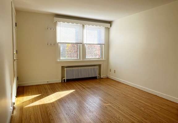 A room with wooden floors and a window with blinds.