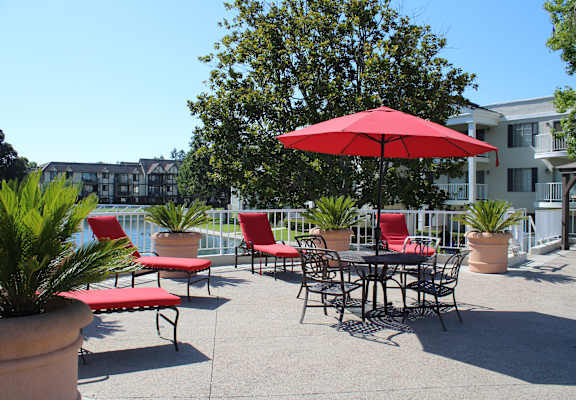 A red umbrella is in front of a table and chairs.