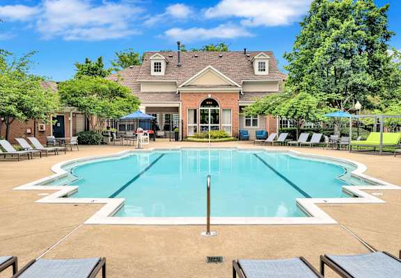 a swimming pool with chairs around it in front of a house