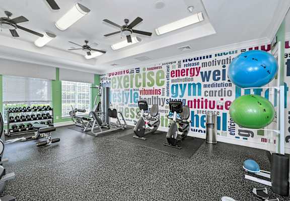 a gym with weights and yoga balls and a wall covered in words