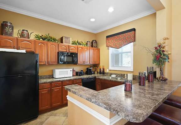 A kitchen with a black refrigerator and wooden cabinets.