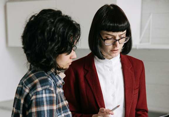 Two people in a laundry room, one holding a tablet.