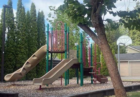 A playground with a slide and a basketball hoop.