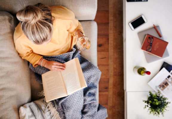 a woman sitting on a couch reading a book