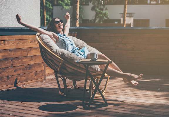Happy woman enjoying the sun outside in a chair at Renew Five Ninety Five, Illinois