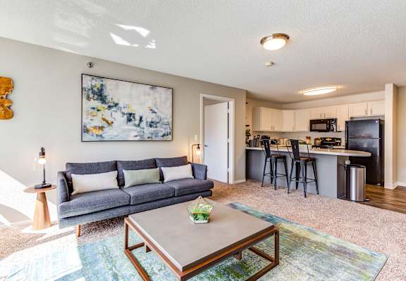 a living room with a couch coffee table and a kitchen in the background