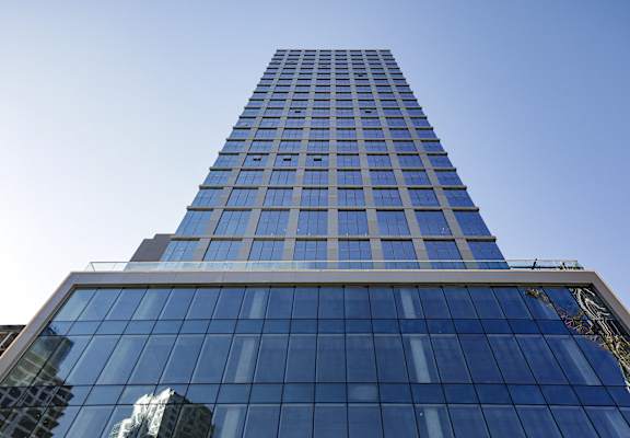 A tall building with blue glass windows stands against a clear sky.