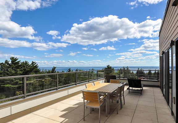 a patio with a table and chairs on a balcony overlooking the ocean at Bluestone Lofts, Minnesota, 55803