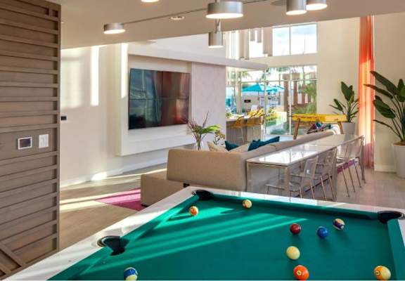A billiard table is in the middle of a room with a television and a couch.
