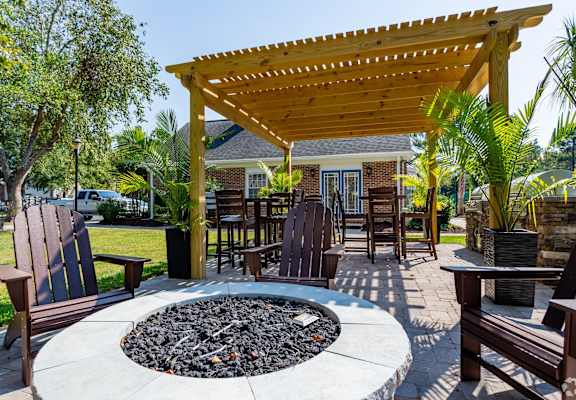 A patio with a fire pit and chairs.