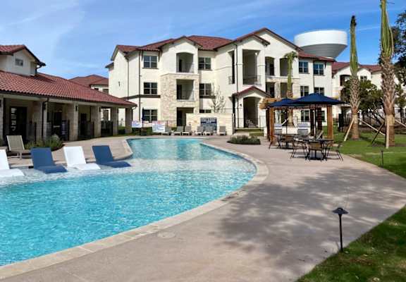 a swimming pool with chairs around it in front of a building