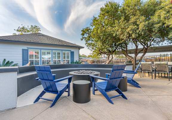 a patio with blue chairs and a fire pit     and a building