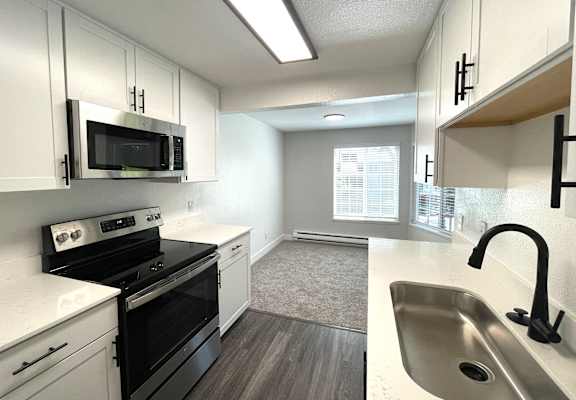 an empty kitchen with white cabinets and black appliances and a sink