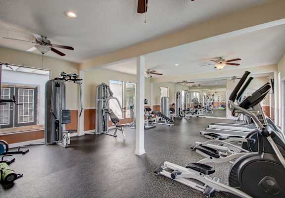 a gym with cardio machines and ceiling fans