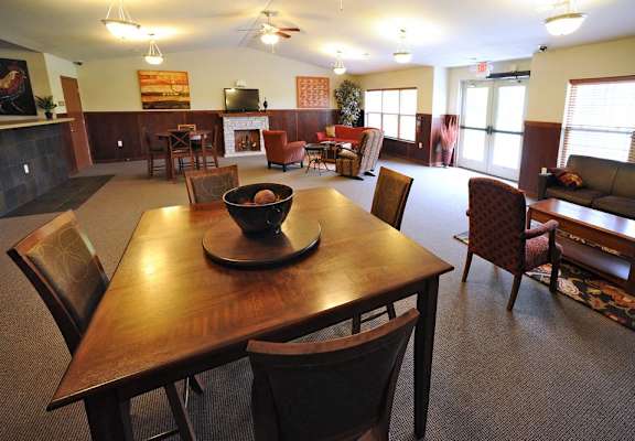 A large wooden dining table with chairs around it in a room with a fireplace.