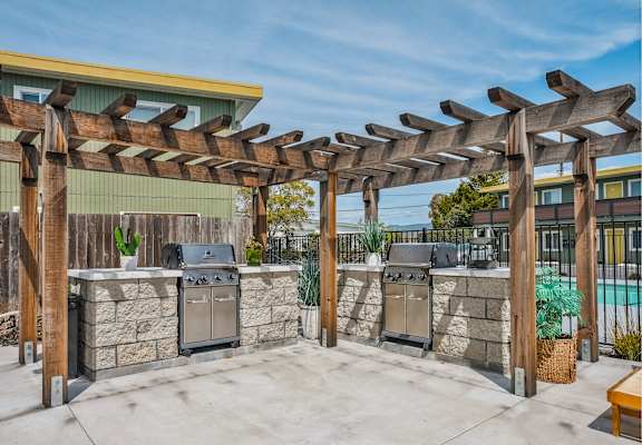 an outdoor kitchen with two stoves and a pergola