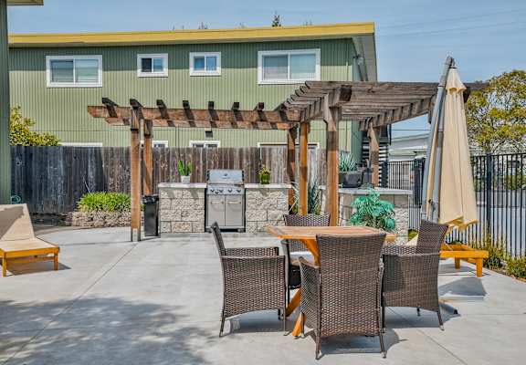 a patio with a table and chairs and a grill