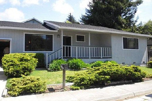 A house with a grey roof and a white wall with a small porch.