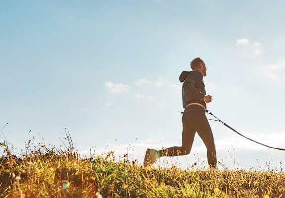 a man walking his dog on a leash in a field
