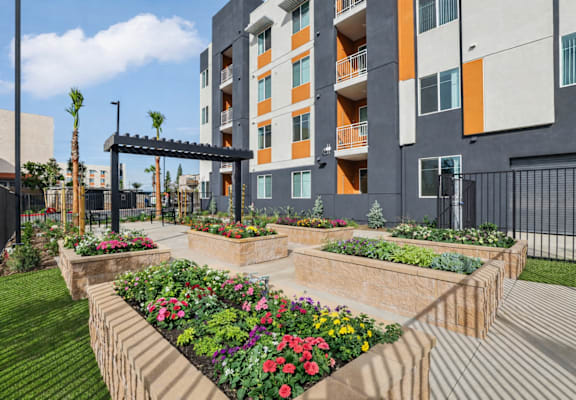 A modern building with a garden in front. at The Orion Senior Apartments - Orange, CA Apartments, California, 92866