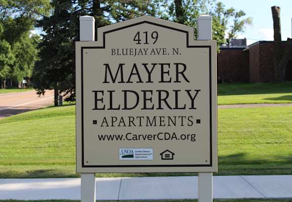 A sign for Mayer Elderly Apartments stands on a sidewalk.