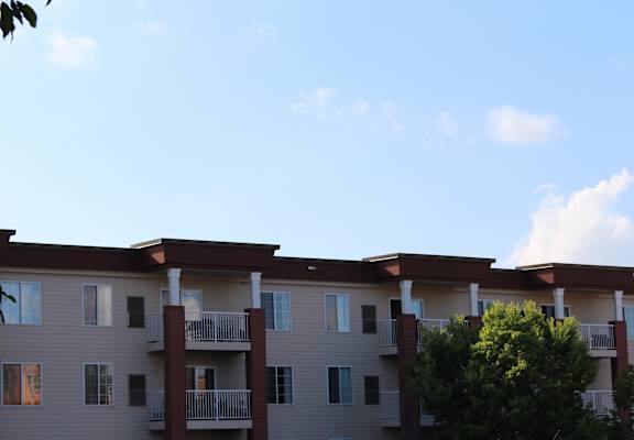 Apartment building with balconies and trees in front.