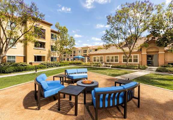 a patio with blue chairs and a fire pit