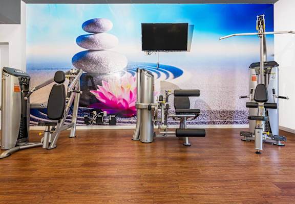 a gym with various machines and a tv in a room