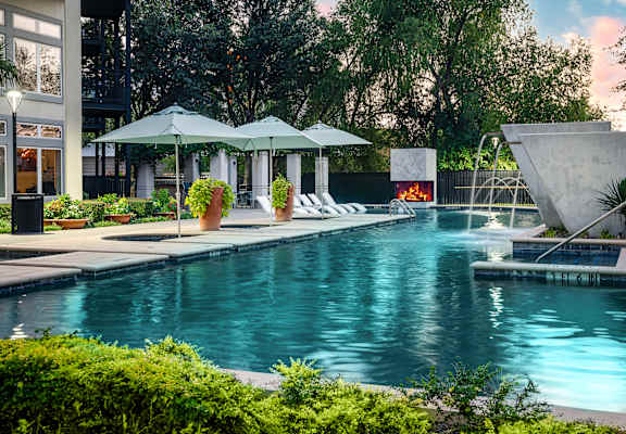 a swimming pool with a fire pit and lounge chairs in front of a building at Trend Design District, Dallas, 75207